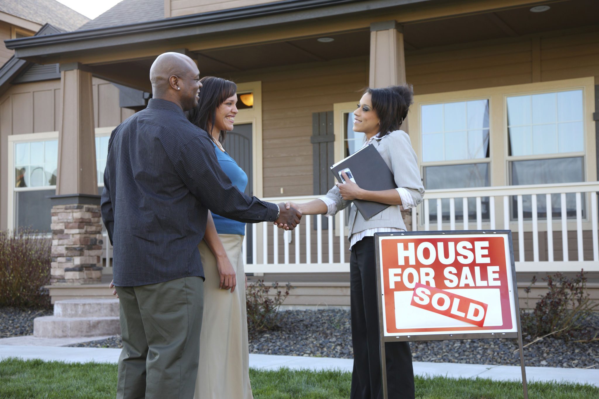 Couple buying house, shaking hands with agent.
